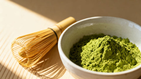 Matcha powder in a bowl with a bamboo whisk.