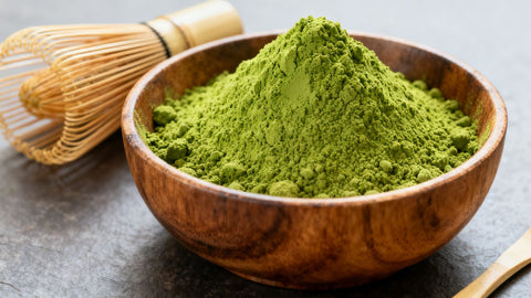 Organic matcha powder in a wooden bowl with whisks.