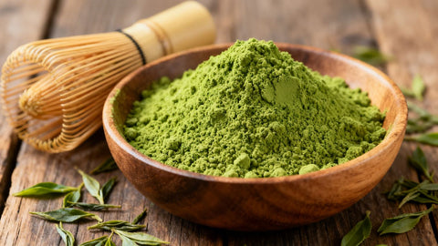 Photograph of matcha powder in bowl with bamboo whisk