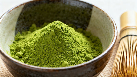 Vibrant green matcha powder in a ceramic bowl with whisk.